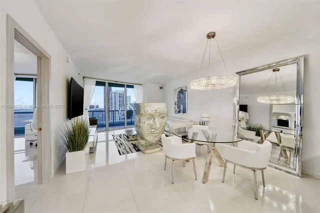 a living room with stainless steel appliances furniture a dining table and a chandelier