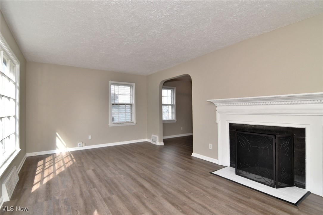 1443 Churchill Road Lyndhurst, OH 44124 - Photo 6 of 39 Unfurnished living room with a fireplace, dark wood-style floors, arched walkways, and a textured ceiling