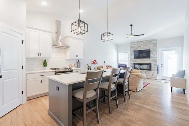 a kitchen with stainless steel appliances a stove a sink a dining table and chairs with wooden floor