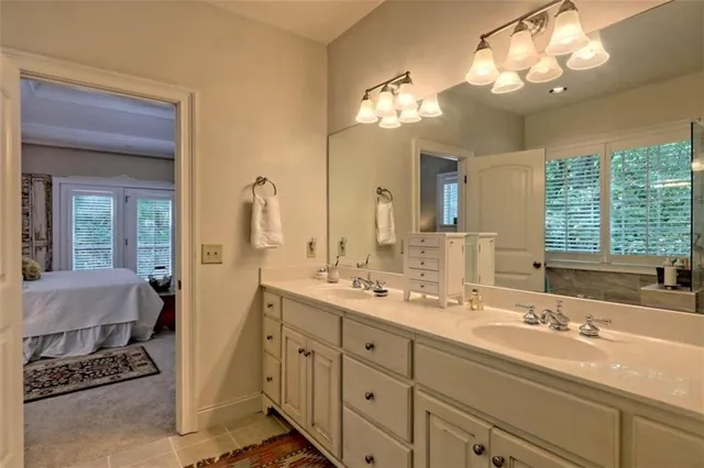 a bathroom with double vanity sink a mirror and a bathtub