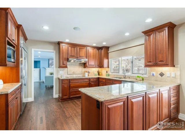 a kitchen with stainless steel appliances granite countertop a refrigerator a sink dishwasher a stove with wooden cabinets and floor