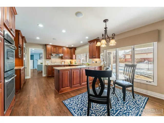 a open kitchen with stainless steel appliances granite countertop a stove a refrigerator a oven a sink with a dining table and chairs