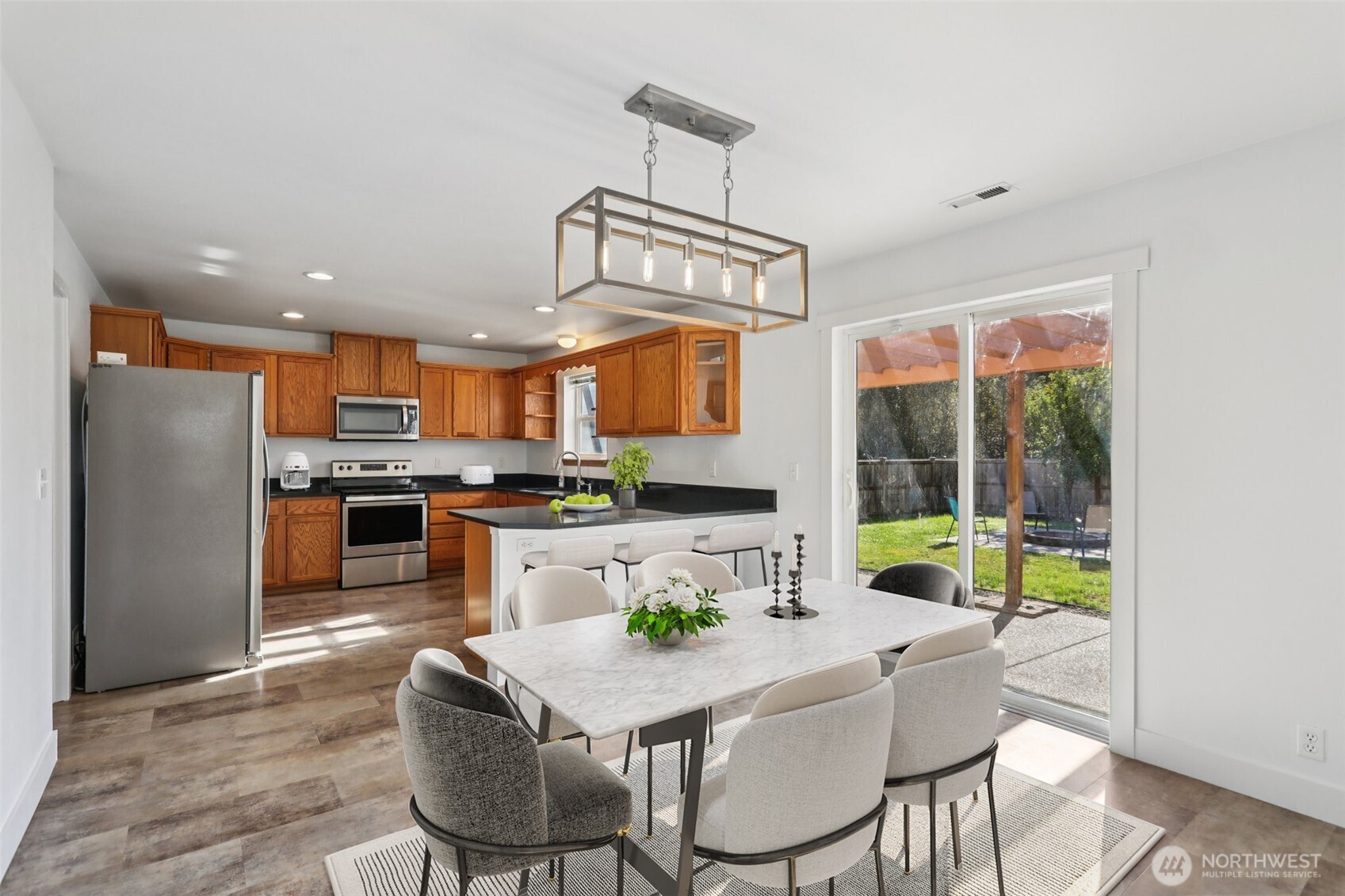 114 Weaver Street Northeast Orting, WA 98360 - Photo 11 of 40 a kitchen with stainless steel appliances granite countertop a stove a refrigerator a kitchen island with a dining table and chairs