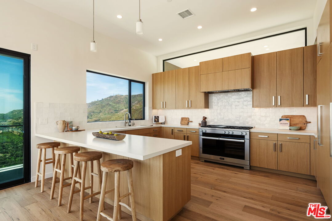 2165 Little Las Flores Road Topanga, CA 90290 - Photo 8 of 40 a kitchen with stainless steel appliances a stove a sink a oven and a refrigerator with wooden floor
