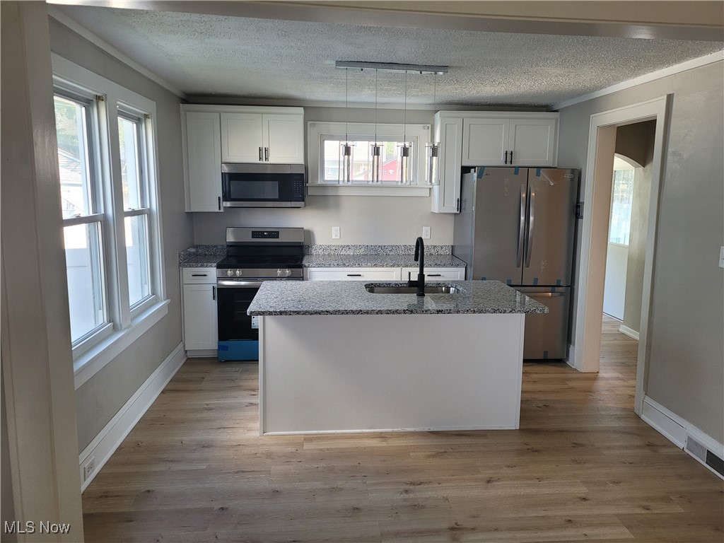 Kitchen with appliances with stainless steel finishes, a textured ceiling, sink, and white cabinets