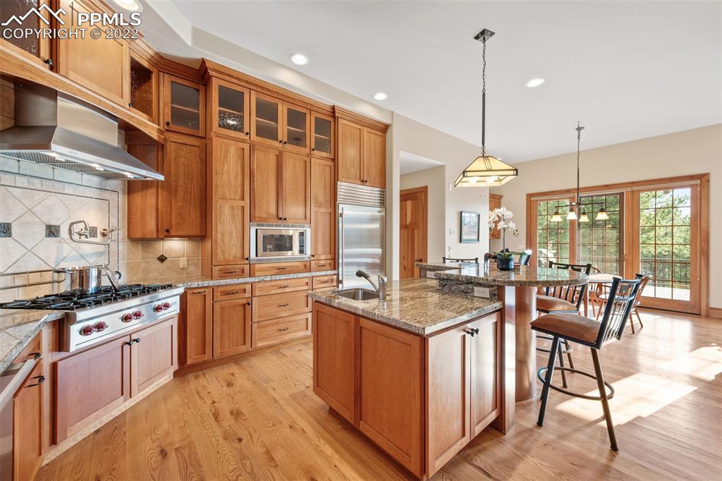 3833 Lorraine Road Larkspur, CO 80118 - Photo 7 of 40 a kitchen with stainless steel appliances granite countertop wooden floors stove top oven and chairs