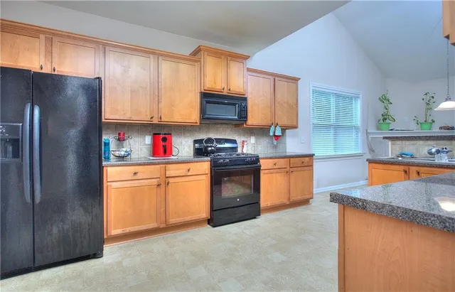 a kitchen with stainless steel appliances granite countertop a refrigerator sink and stove