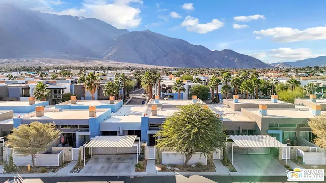 a view of a patio with couches and table and chairs under an umbrella with a view of city
