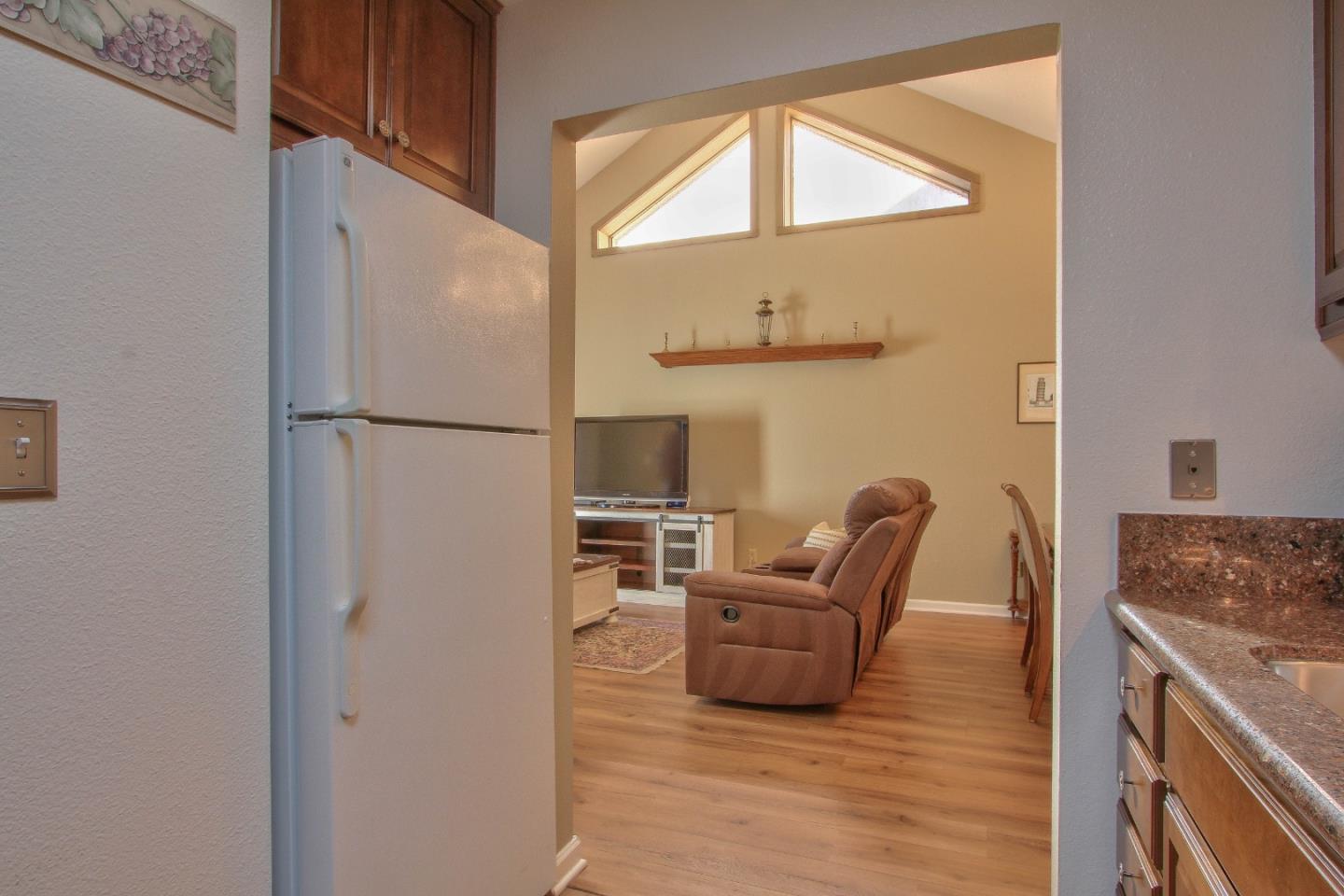 4000 Rio Road, Unit 26 Carmel, CA 93923 - Photo 11 of 27 a kitchen with stainless steel appliances granite countertop a refrigerator a stove a sink and a dining table with wooden floor