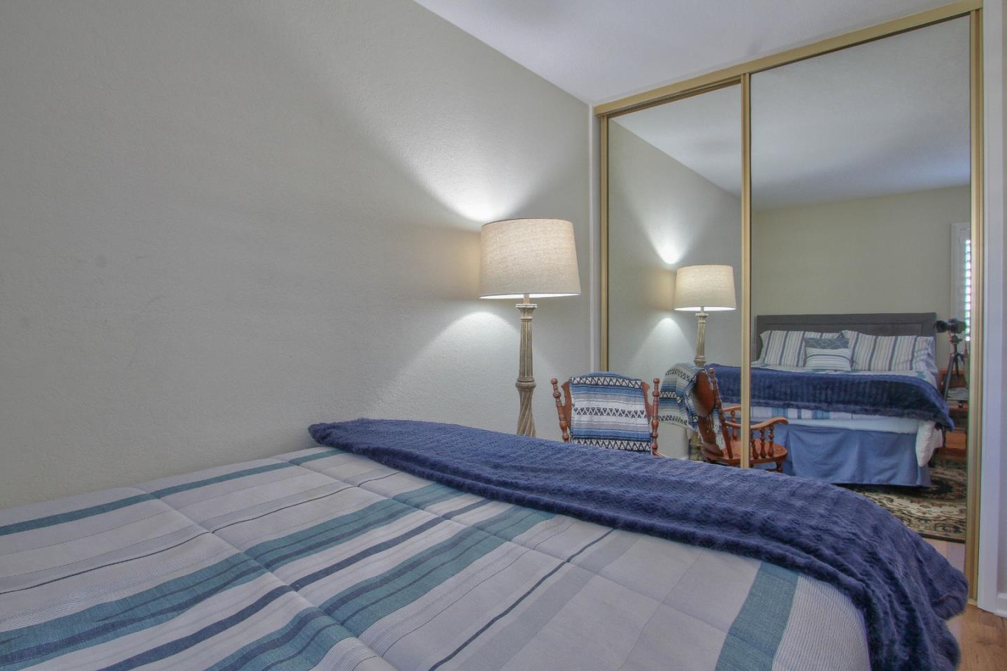 4000 Rio Road, Unit 26 Carmel, CA 93923 - Photo 18 of 27 a bedroom with a bed a mirror and lamp