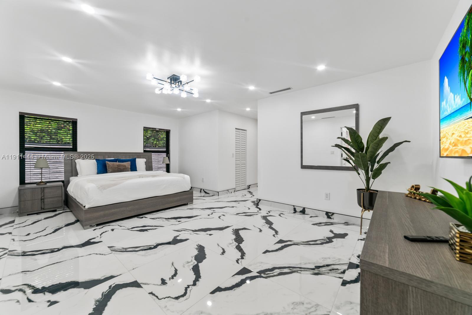 14242 Southwest 30th Street Miami, FL 33175 - Photo 27 of 45 a bedroom with a large bed and a chandelier