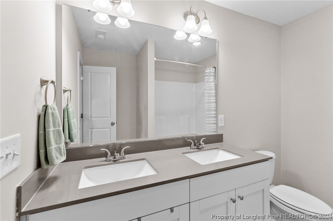 740 Walker Road Bunnlevel, NC 28323 - Photo 12 of 27 a bathroom with a granite countertop sink a toilet and a mirror