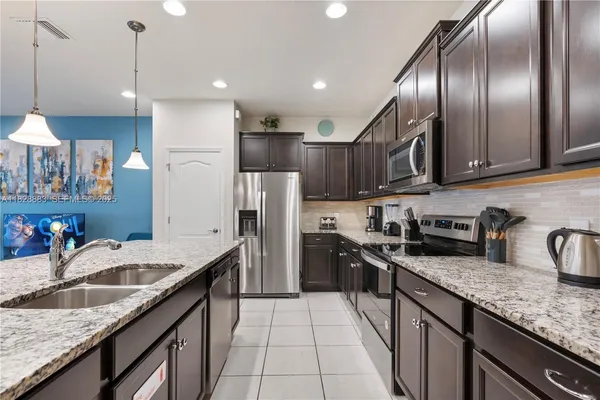 a kitchen with stainless steel appliances granite countertop a sink a stove and a refrigerator
