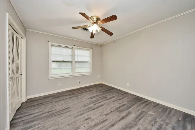 an empty room with wooden floor fan and windows