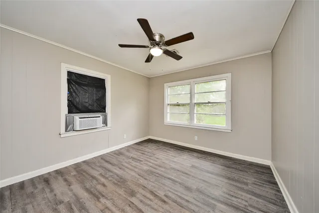 a view of empty room with wooden floor and fan