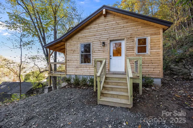 a view of a house with a yard chairs and wooden fence