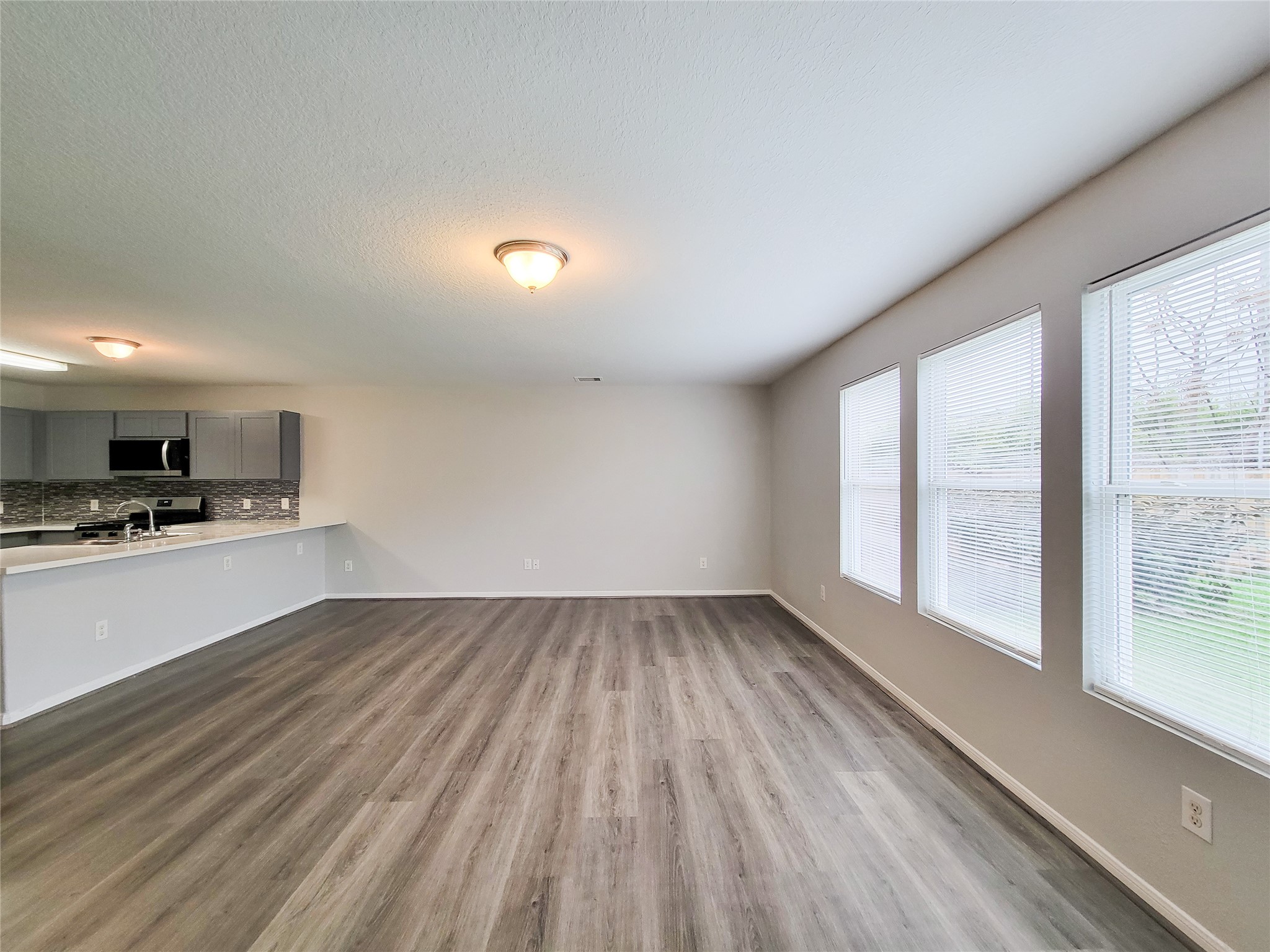 3602 Zephyr Glen Way Houston, TX 77084 - Photo 16 of 42 a view of kitchen and empty room with wooden floor and windows