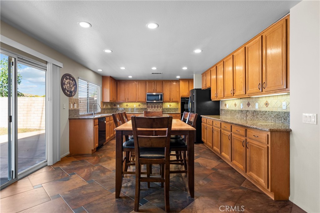 32810 The Old Road Castaic, CA 91384 - Photo 15 of 45 a kitchen with kitchen island granite countertop wooden cabinets a dining table and chairs
