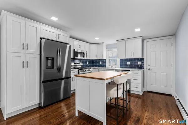 a kitchen with stainless steel appliances granite countertop a refrigerator a sink dishwasher a stove and a refrigerator with wooden floor