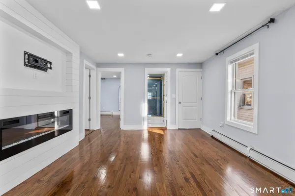 a view of an empty room with window and wooden floor