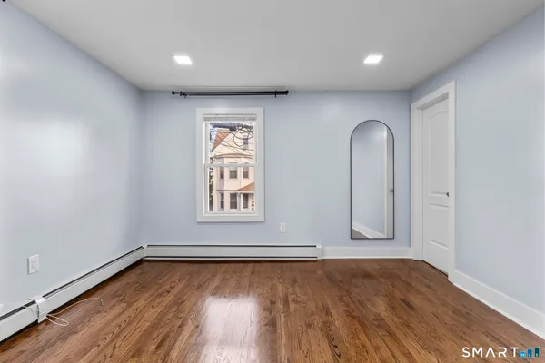 an empty room with wooden floor and window