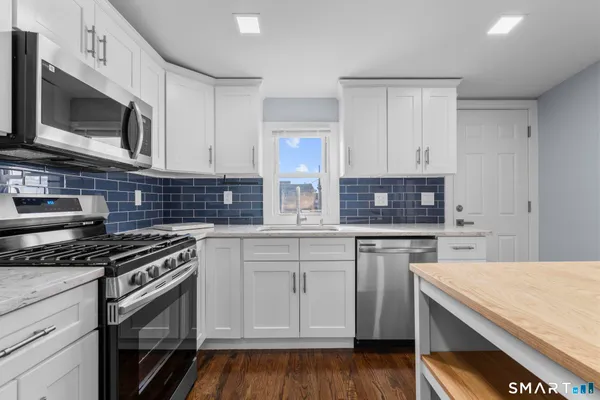 a kitchen with stainless steel appliances granite countertop a stove microwave and cabinets