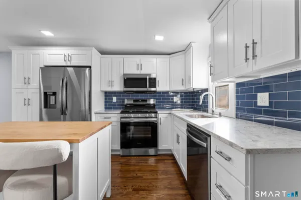 a kitchen with stainless steel appliances granite countertop a sink stove microwave and refrigerator