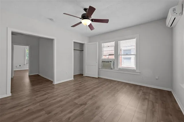 an empty room with wooden floor chandelier fan and windows