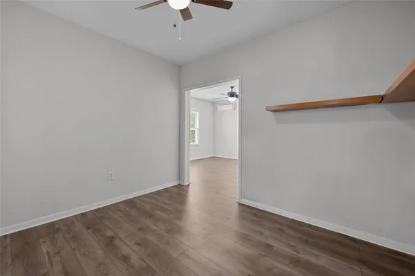 an empty room with wooden floor and chandelier fan