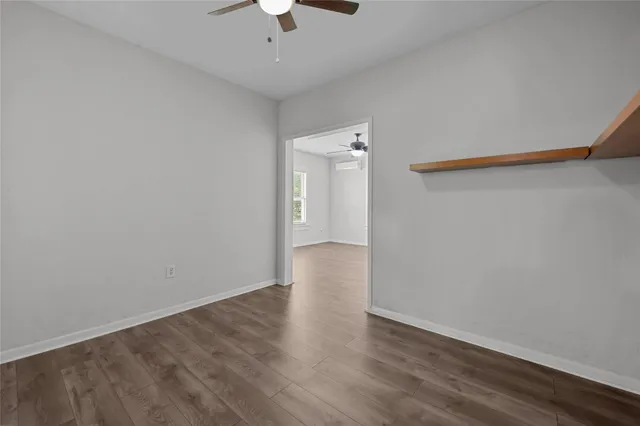 an empty room with wooden floor and chandelier fan