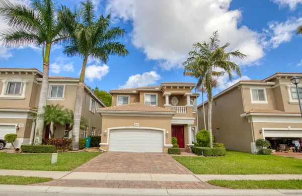 a front view of a house with a garden and palm trees