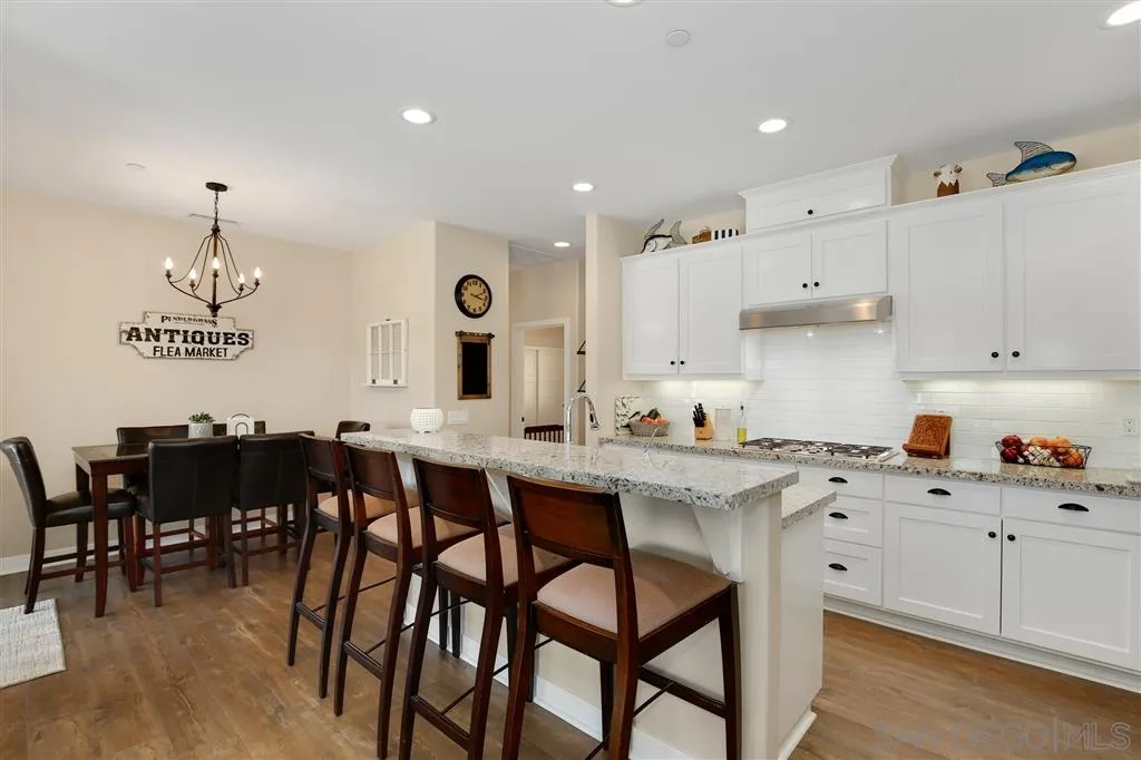 12972 Anthony Ridge Road Valley Center, CA 92082 - Photo 7 of 25 a kitchen with a dining table chairs and white cabinets