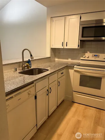 a kitchen with stainless steel appliances granite countertop a sink a stove and a refrigerator