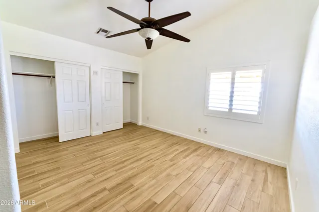 a view of empty room with wooden floor and fan