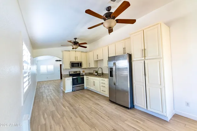a kitchen with stainless steel appliances wooden floor and a refrigerator