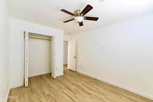 an empty room with wooden floor and ceiling fan