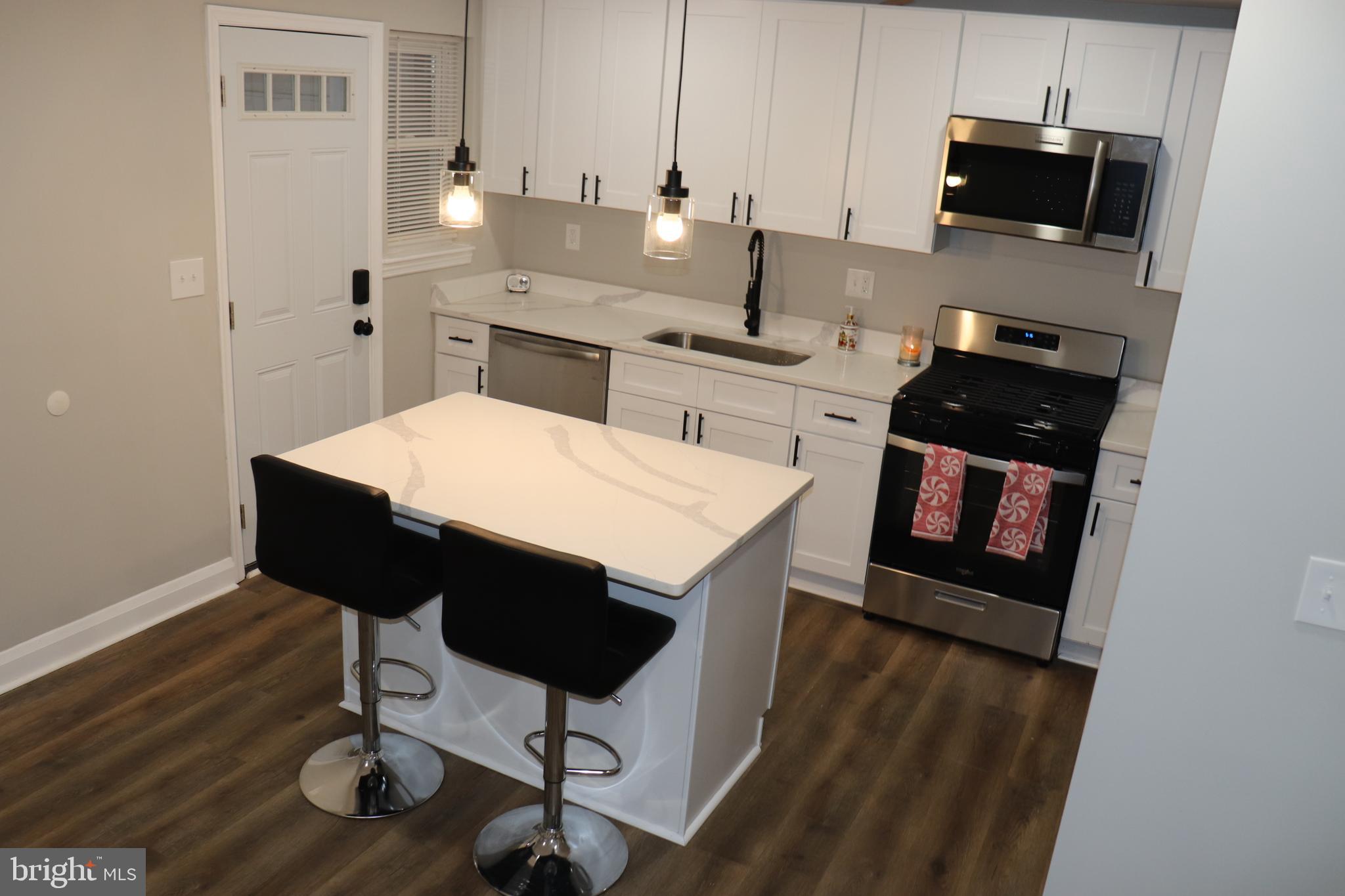 8623 Willow Oak Road Parkville, MD 21234 - Photo 4 of 27 a kitchen with stainless steel appliances a stove a refrigerator white cabinets and wooden floor