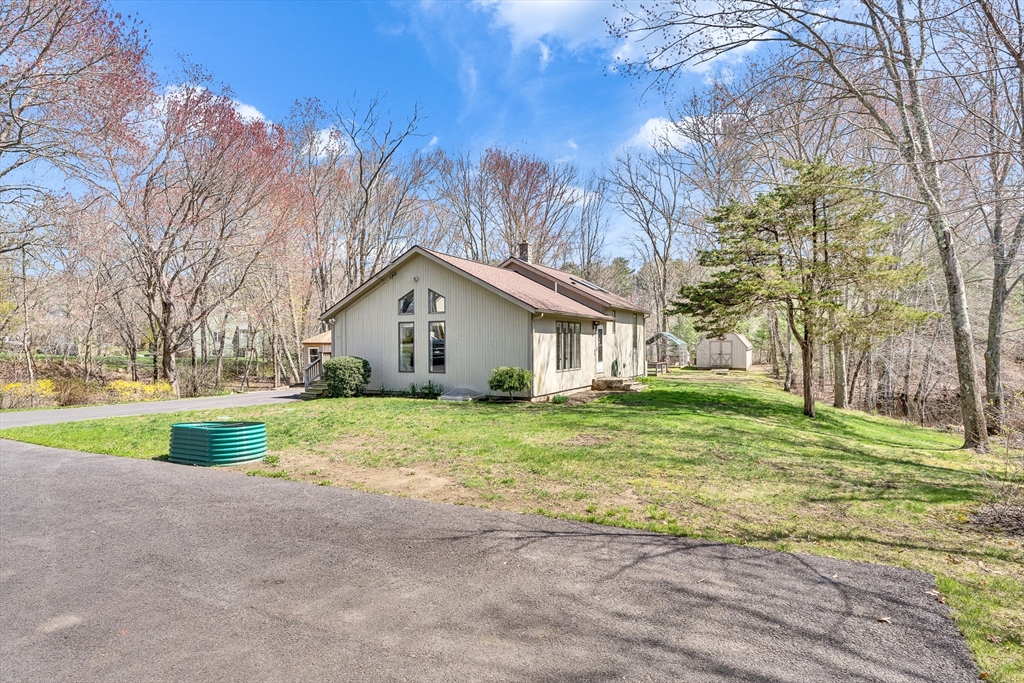 a view of a house with a yard and large trees