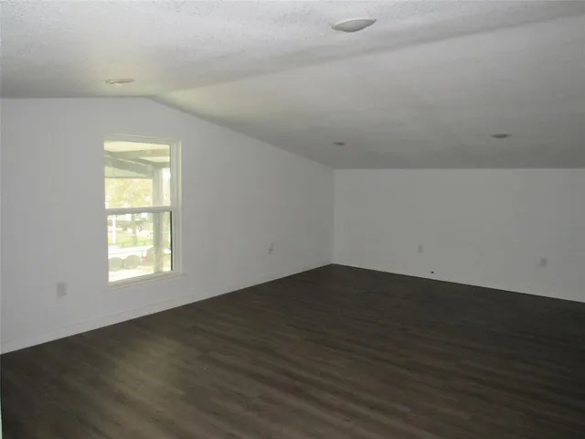 an empty room with wooden floor and window