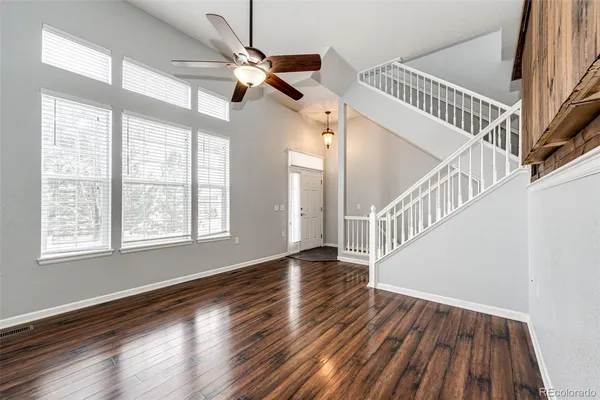 a view of empty room with wooden floor and fan