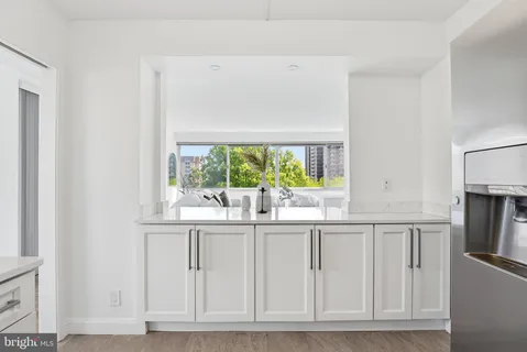 a kitchen with white cabinets and window