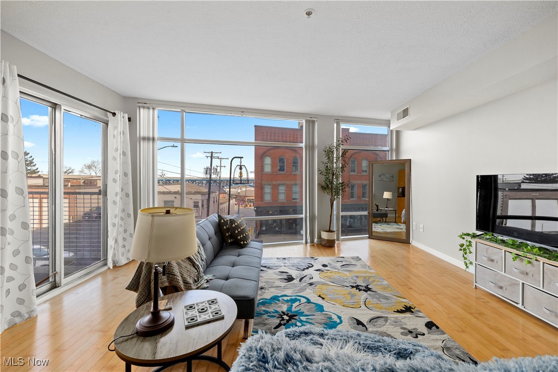 2222 Detroit Avenue, Unit 519 Cleveland, OH 44113 - Photo 2 of 30 Living area featuring a balcony, expansive windows, and finished hardwood floors