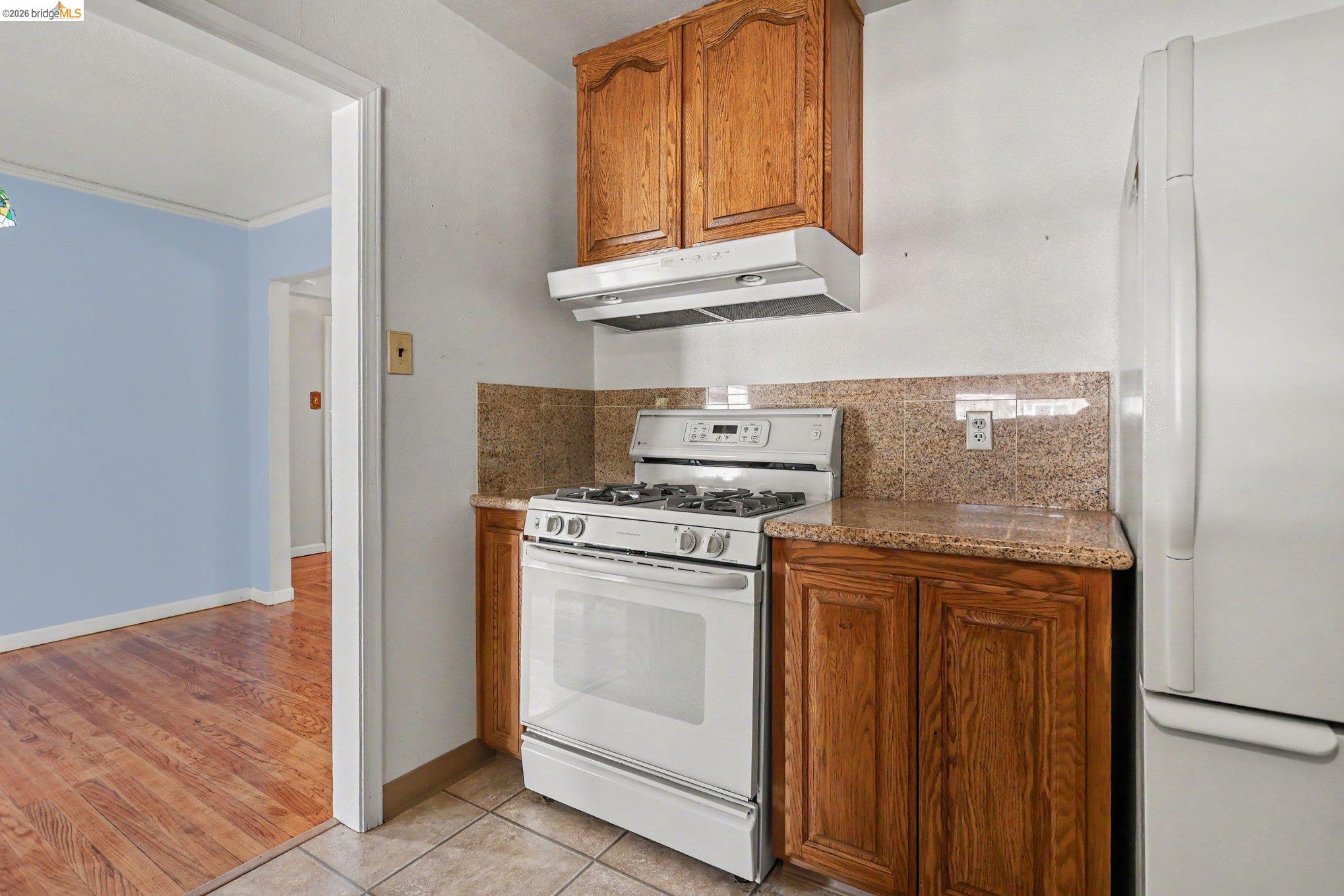 249 Madison Avenue Bay Point, CA 94565 - Photo 10 of 18 Kitchen featuring wood cabinetry, a white gas range with overhead ventilation, and a white refrigerator