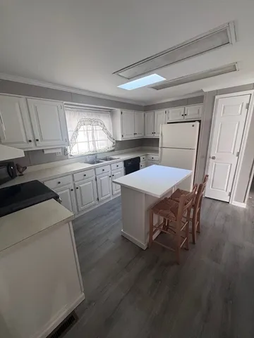 a kitchen with a table chairs a sink dishwasher stove and cabinets with wooden floor