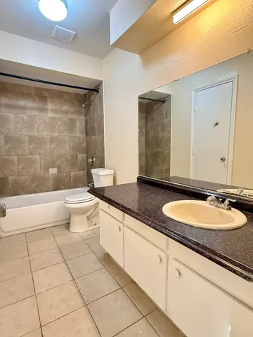 a bathroom with a granite countertop sink a toilet a mirror and bathtub
