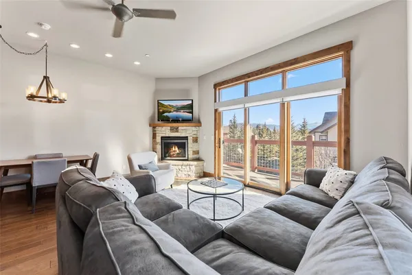 a living room with furniture a ceiling fan and a floor to ceiling window
