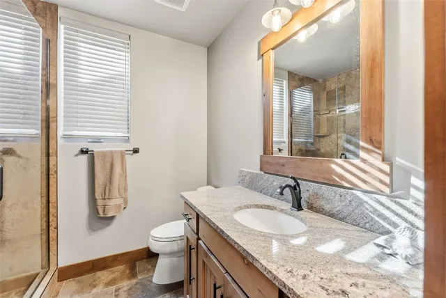 a bathroom with a granite countertop sink toilet and shower