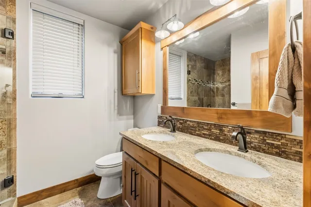 a bathroom with a granite countertop toilet a sink and a mirror