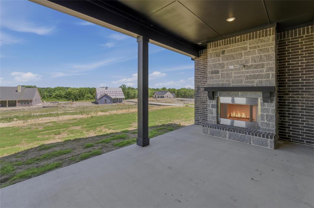 815 Vly Rdg Road Van Alstyne, TX 75495 - Photo 24 of 29 Covered outdoor patio featuring a concrete surface, a built-in fireplace with a stone surround and wood mantel, recessed lighting, and dark brick exterior