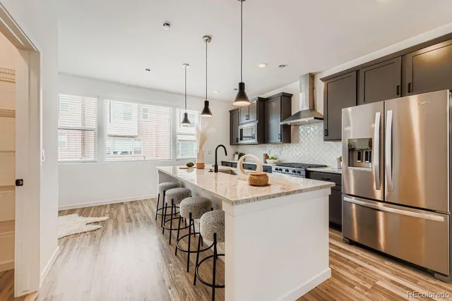 a kitchen with stainless steel appliances granite countertop a refrigerator a sink a stove and a wooden floors